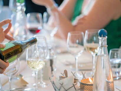 Pessoa servindo vinho branco em taça de vinho transparente