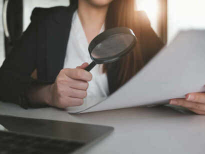 A journalist using a magnifying glass to carefully examine a document for fact-checking