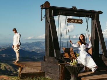Um casal contempla a paisagem montanhosa a partir de um espaço de madeira, cercado pela natureza. A imagem evoca a ideia de intimidade romântica, que o artigo contrapõe à relação destrutiva entre Heathcliff e Catherine