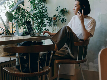 In a cozy café, a woman wearing a white shirt sits by herself while making a phone call