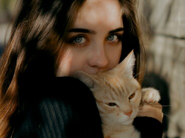 Mulher abraça um gato ruivo, em uma imagem que aproxima afeto e convivência entre pessoa e animal. No texto, o termo “gata” ganha um sentido figurado quando deixa de designar o animal e passa a caracterizar uma pessoa, mostrando como o contexto pode transformar o sentido das palavras