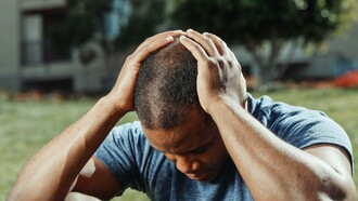 Homem pensa com a cabeça entre as mãos