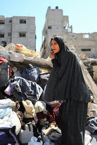 A woman navigates the ruins of her former home, a poignant image of resilience amid widespread destruction during war