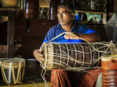 A man is busy making a traditional drum.  Village Kuragala in Sri Lanka has acquired an extraordinary style of drumming over the centuries, one of the loudest and most exuberant in the world