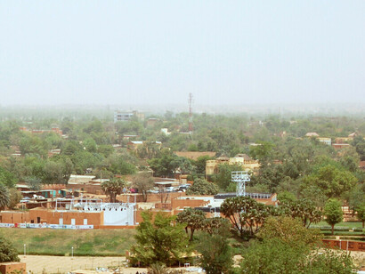 Vue depuis la Grande Mosquée de Niamey au Niger. De l'autre côté de la route se trouvent des étals de marché, un amphithéâtre en plein air (équipé de projecteurs) et une vue sur la ville.