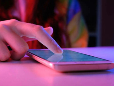 A woman using her cell phone to read news and engage in online activism, sharing political memes and viral content