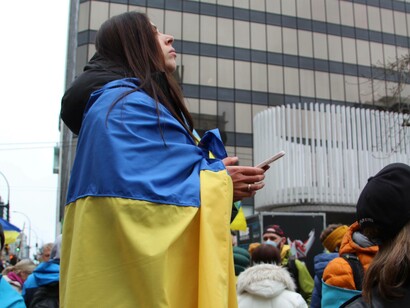 A woman in the Grand Place square in Brussels, Belgium draped in the colors of the Ukrainian flag