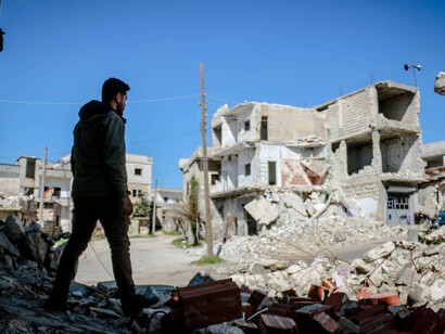 A man walks through a city of destroyed houses in Idlib, Idlib Governorate, Syria