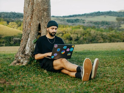 Com o computador no colo, um profissional desenvolve suas atividades fora do ambiente tradicional de escritório. O artigo propõe uma reflexão sobre as oportunidades e os desafios trazidos pelos novos modelos de trabalho