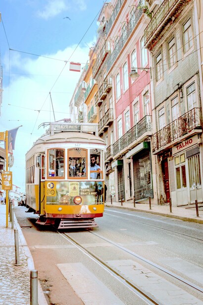 Bonde amarelo e branco perto de edifícios de concreto, em Lisboa, Portugal