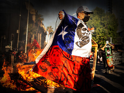 Hombre cubierto con la bandera de Chile participa en una protesta durante el Estallido Social de 2019
