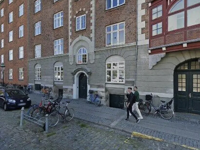 El paso de una arquitectura que se transmitía y se deformaba con el tiempo a otra que se ejecuta en un presente continuo, siempre actualizable, siempre optimizable. En una calle y vereda de piedras, 2026, Copenhague, Dinamarca