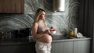 A medium shot of a pregnant woman enjoying a fruit bowl, emphasizing the benefits of nutritious food choices during pregnancy for both mother and baby