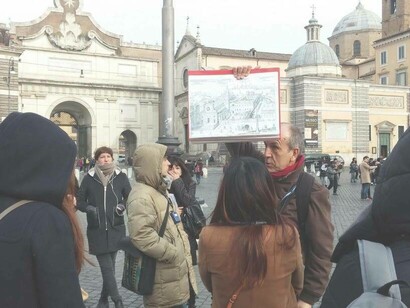 Alberto Tagliaferri at Piazza del Popolo, holding a diagram showing  Santa Maria del Popolo Church and what the area used to look like in the 1600s