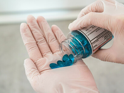A blue pill resting on a palm, visually connecting pharmaceutical treatment with genetic and molecular health