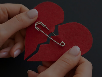 High angle of person holding broken heart put back together with safety pin