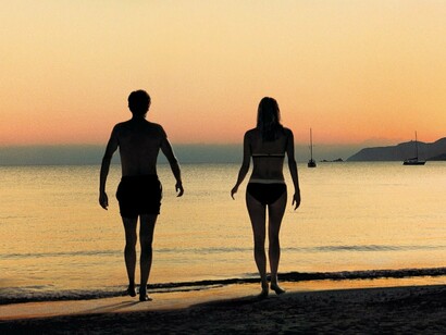 Una pareja pasea junto al mar al atardecer