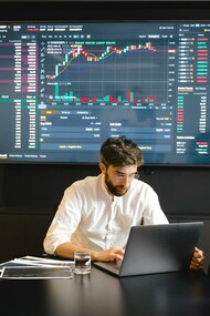 Trader analisando gráfico da bolsa de valores no laptop