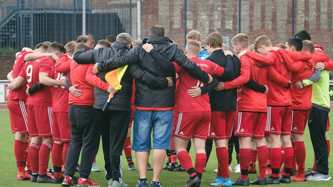 A soccer team stands in a circle with their coach, showing camaraderie, support, and team bonding before a match