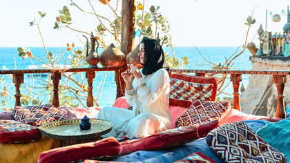 A visitor savouring tea amid traditional Moroccan décor overlooking the coast, reflecting how cultural experiences contribute to a country’s tourism identity