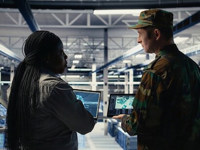 An army commander and a software developer use an AI-powered radar system in a data center