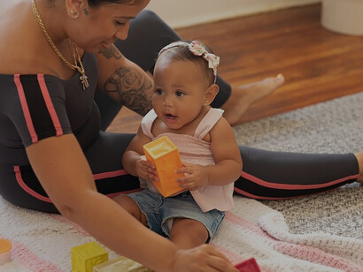 Amidst a cozy scene, a person delights in playful moments with a charming baby on the floor