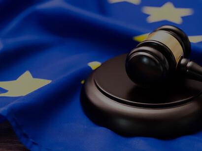 Upon the table lies a wooden gavel positioned next to the flag of the European Union