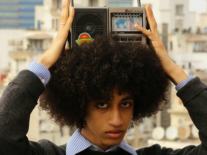 Garoto típica dos anos 1990 com aparelho de rádio. Nos anos 1990, era comum esperar pelo lançamento de um álbum físico ou ouvir uma música repetidamente nas rádios. Hoje, plataformas digitais permitem acesso imediato a milhões de faixas, mas a ansiedade pelo lançamento de novos trabalhos de artistas ainda permanece