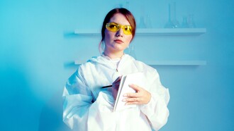 Uma mulher cientista vestindo jaleco enquanto segura um caderno