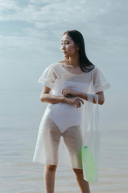 Modelo com roupa de plástico no mar. A conscientização do consumidor desempenha um papel crucial na adoção de práticas sustentáveis