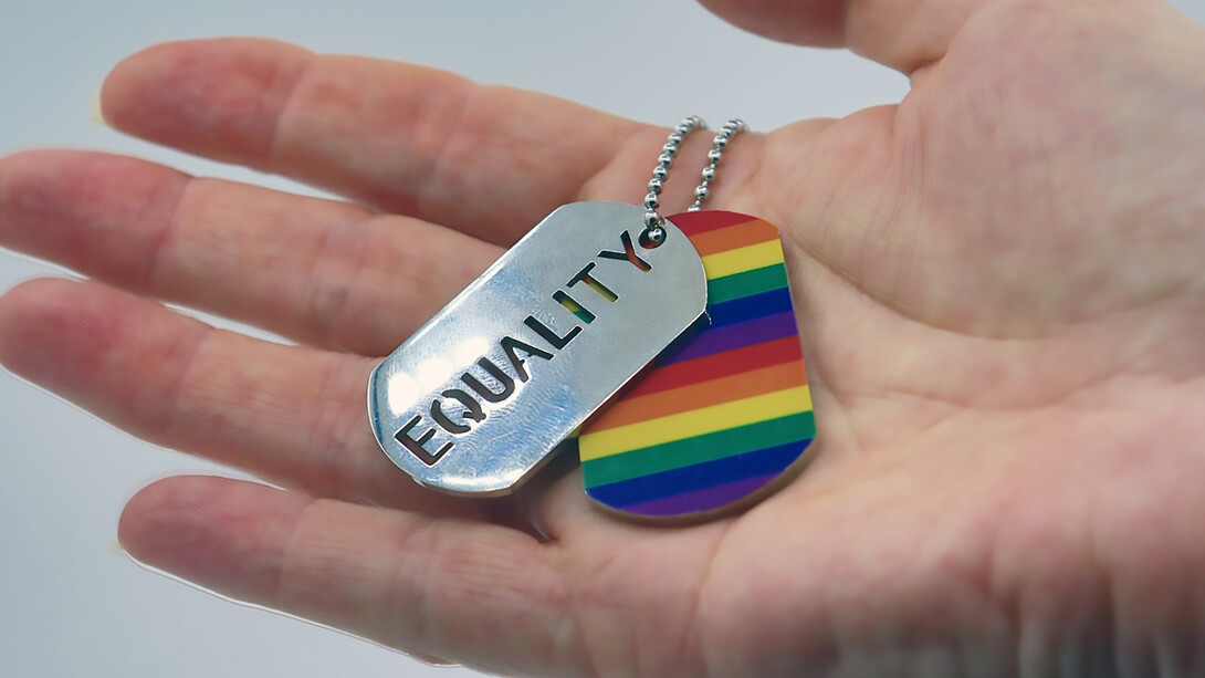 A person holding a rainbow tag in their hand, symbolizing the equality