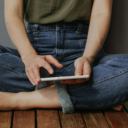 A person reading an e-book while relaxing on a wooden deck