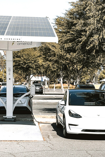 Row of electric vehicles plugged into solar-powered charging stations