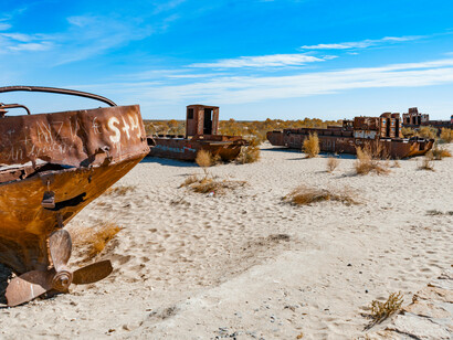 A rusted abandoned ship rests in the desert landscape of Muynaq, Uzbekistan, reflecting the devastating environmental transformation of the Aral Sea region