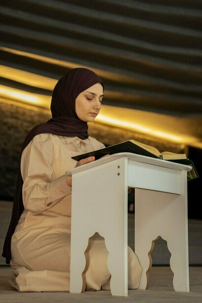 A young woman immersed in reading the Quran, representing the pursuit of Islamic knowledge and spiritual devotion