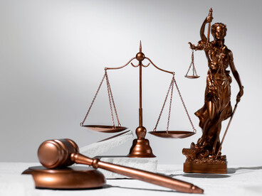 The scales of justice and a scale standing above a judge's gavel, representing the rebuilding of legal order after institutional instability
