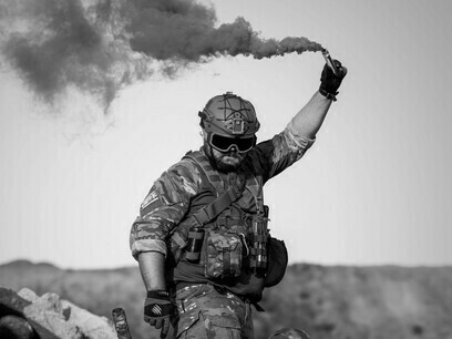 Ein Soldat gibt mit einer Rauchfackel inmitten eines verwüsteten Schlachtfelds ein Zeichen und verdeutlicht damit die menschlichen Kosten globaler Konflikte und die sich verändernde Dynamik der internationalen Ordnung