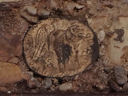 La seconda moneta, che potrebbe essere un sesterzio dell’età di Traiano (98 – 117 d. C.) o di Lucio Vero (161 – 169 d. C.), riporta al rovescio la personificazione della Victoria romana, corrispondente alla Nike greca, rappresentata come una figura femminile alata che tiene uno scudo iscritto, posto su un albero di palma in segno di trofeo, foto di Francesco Ferlaino
