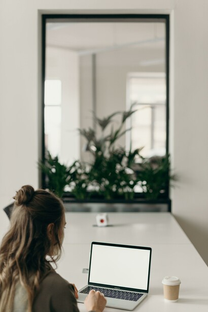 Woman looking at her laptop with a drink