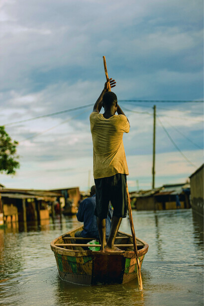 A wooden canoe carrying people passing destroyed homes, reflecting the growing challenges posed by El Niño-driven flooding events