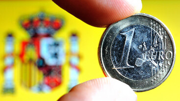 Moneda de un euro con la bandera española al fondo