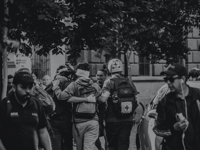Black and white image of an injured protestor with medical staff