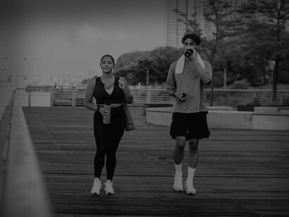 A woman and a man walking for exercise on pier, drinking water