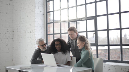 Sports managers collaborate around a computer, strategizing the future of sport management in an ever-evolving industry