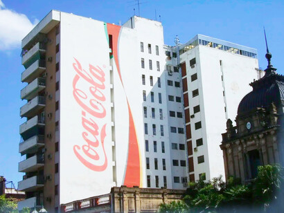 The larger-than-life Coca-Cola logo on the building next to the government building in Tucumán, Argentina