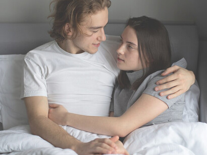 Romantic partners in bed with a tender embrace, highlighting intimacy and bond in their relationship