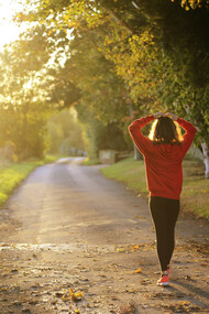 A young woman walking along a sunlit path, setting goals to develop healthier habits