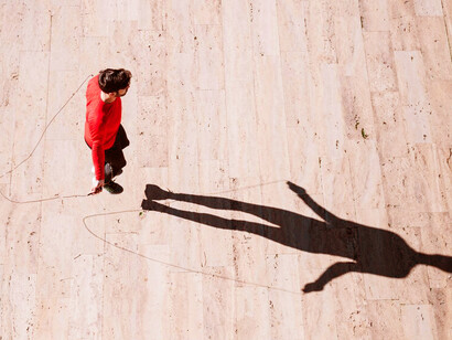 A man jumping rope, casting a shadow above him