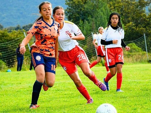 A passionate women’s youth football team in motion, symbolising the simplicity and thrill of the game