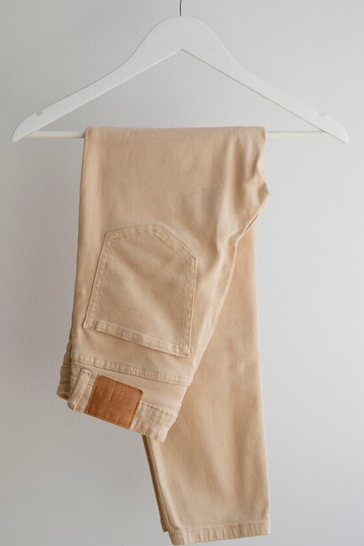 A hand holding a pair of light brown beige pants